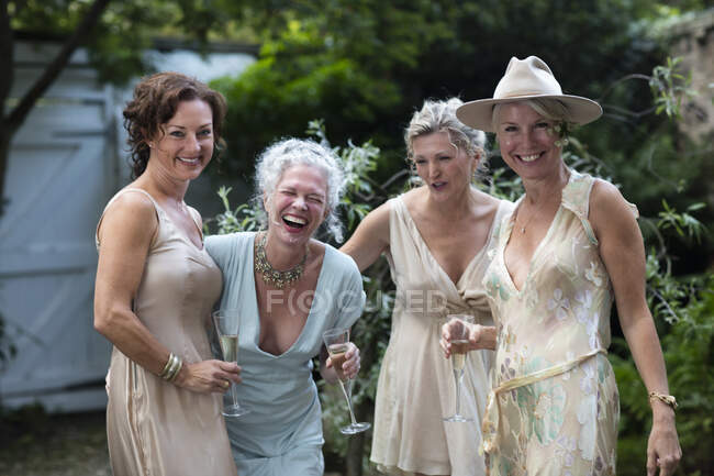 Elegant mature women enjoying champagne in urban garden — Stock Photo
