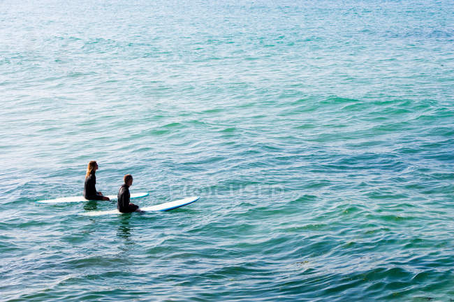 Couple sitting on surfboards — Stock Photo