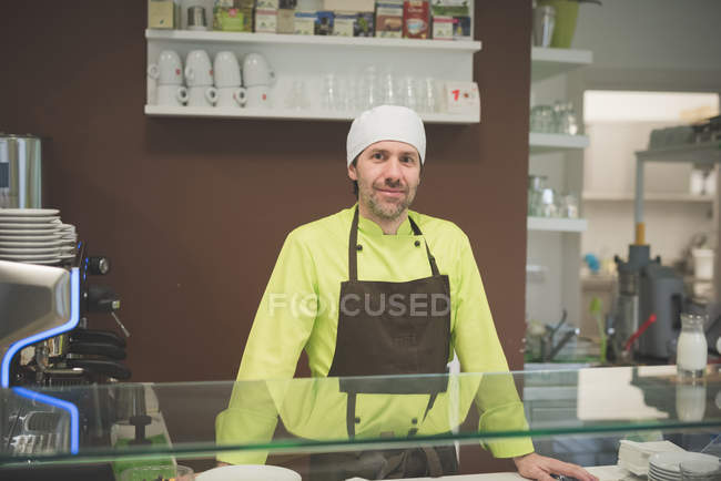 Waiter working at cafe, standing at counter and looking in camera — Stock Photo