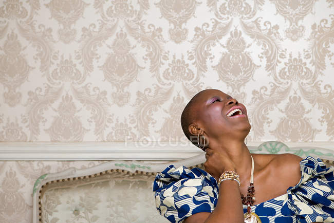 Портрет смеющейся африканки, сидящей на диване — стоковое фото