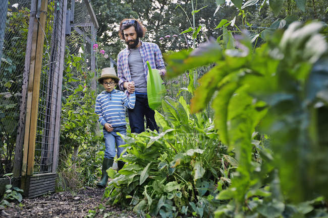Pai e filho regando plantas na colocação — Fotografia de Stock