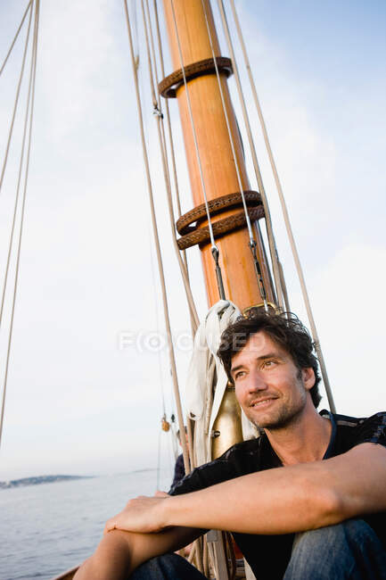 Людина сидить на палубі вітрильного човна — стокове фото