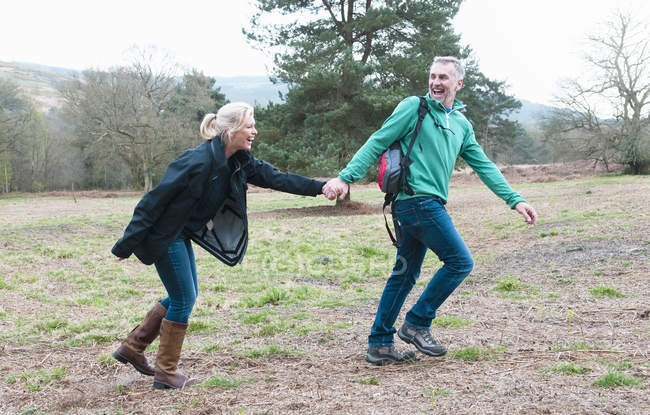 Escursioni coppia tenendosi per mano e correndo in campo — Foto stock