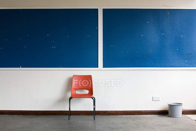 Cadeira vermelha vazia ao lado da mesa em sala de aula — Fotografia de Stock