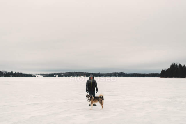 Portrait of man standing with husky dog in snow covered landscape — Stock Photo
