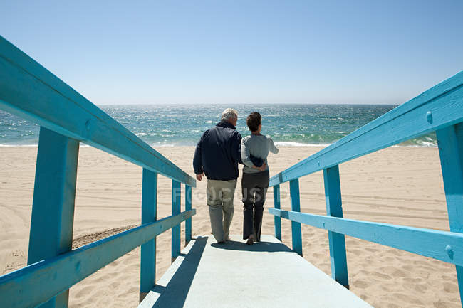 Visão traseira do casal na passarela da praia — Fotografia de Stock