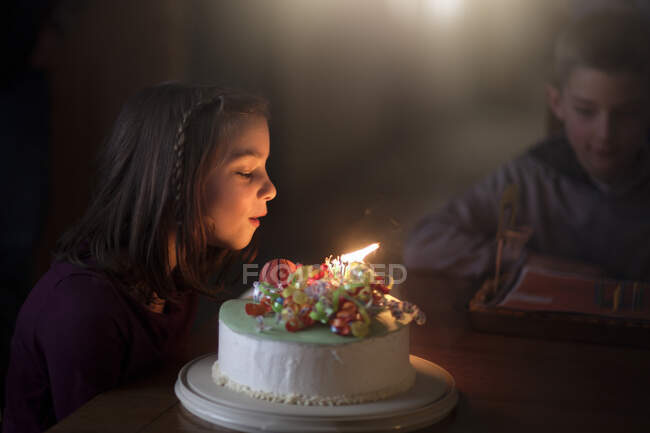 Mädchen bläst Kerzen auf Geburtstagstorte aus — Stockfoto