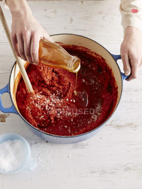 Overhead view of mid adult womans adding liquid to gochuchang in a saucepan — Stock Photo
