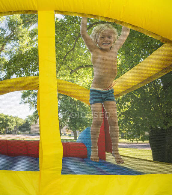 Boy jumping on bouncy castle looking at camera smiling — Stock Photo
