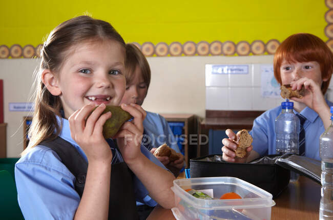 Дети в школе едят упакованные обеды — стоковое фото