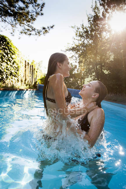 Duas adolescentes pulando e salpicando na piscina — Fotografia de Stock