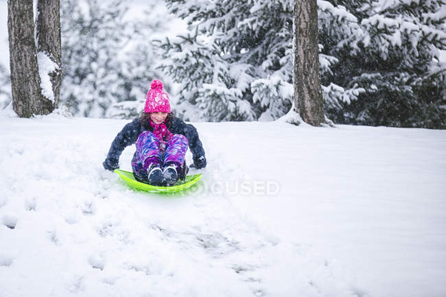 Menina tobogganing downhill no inverno — Fotografia de Stock