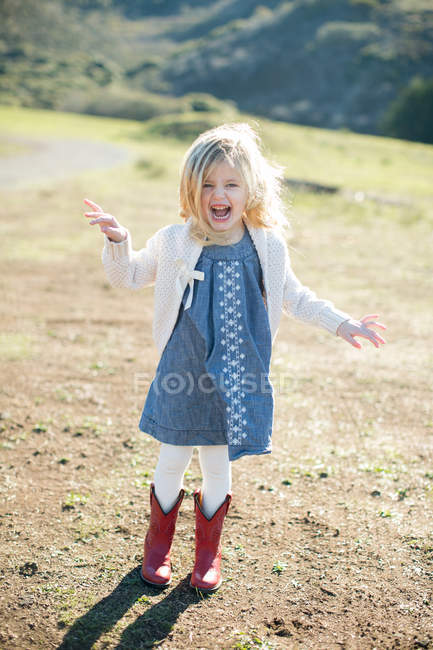 Portrait of girl in field wearing red cowboy boots — Stock Photo