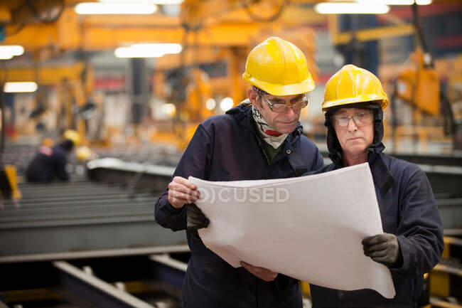 Arbeiter lesen Baupläne in Werft — Stockfoto