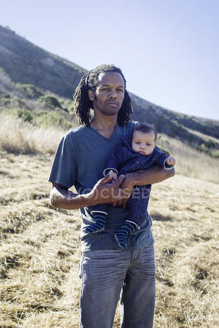 Портрет отца, стоящего на пляже, держащего мальчика — стоковое фото