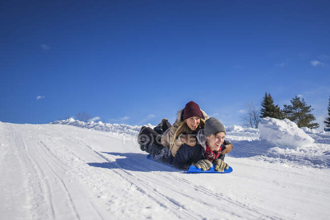 Two friends sliding downhill on crazy carpet, Montreal, Quebec, Canada — Stock Photo