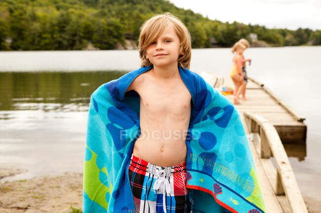 Мальчик на пирсе с полотенцем — стоковое фото