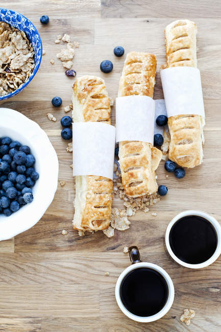 Pâtisseries cuites au four, bleuets et tasses à café noires sur la table — Photo de stock
