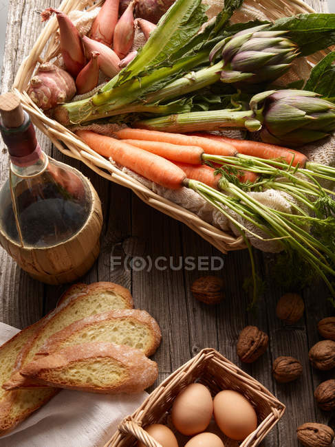 Cesta de verduras con huevos y rebanadas de pan en la mesa - foto de stock