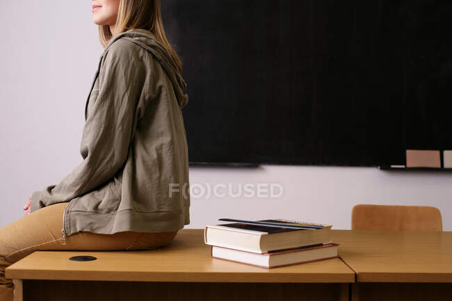 Giovane donna seduta sul bordo della scrivania — Foto stock