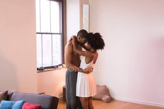 Casal abraçando na sala de estar — Fotografia de Stock