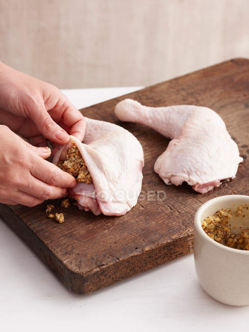 Manos rellenando patas de pollo - foto de stock