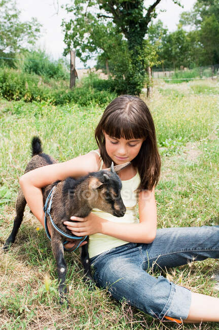 Girl with goat kid in field — Stock Photo