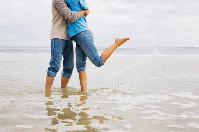 Imagen recortada de Pareja abrazándose en el mar - foto de stock