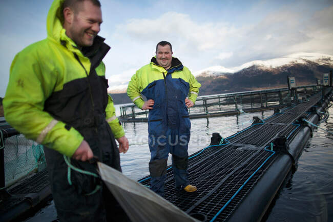 Trabajadores de la piscifactoría de salmón en lago rural - foto de stock