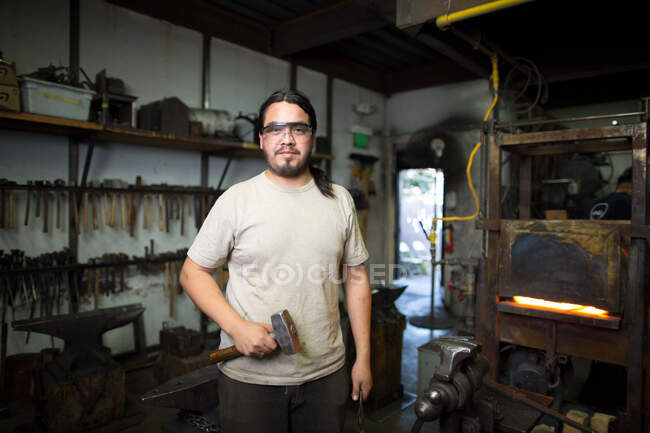 Portrait of male metalsmith by metal workshop furnace — Stock Photo