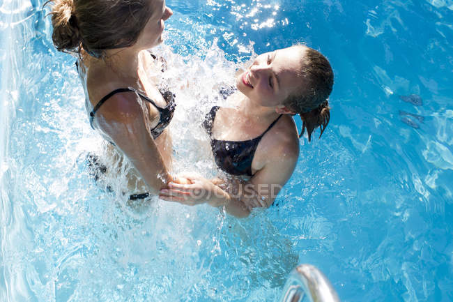 Teenage girls splashing in swimming pool — Stock Photo