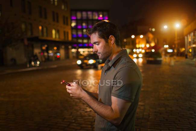 Man using cell phone on city street — Stock Photo