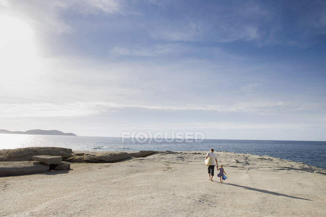 Hombre maduro paseando con su hija pequeña en la playa, Calvi, Córcega, Francia - foto de stock