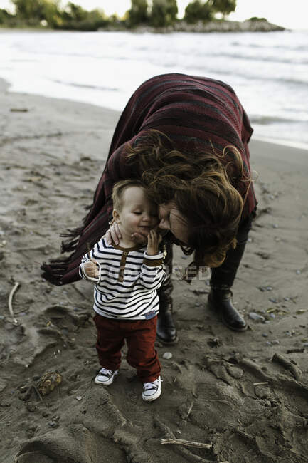 Mãe na praia beijando bebê menino na bochecha, Toronto, Ontário, Canadá — Fotografia de Stock