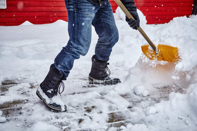Человек убирает снег с пути, низкий участок — стоковое фото