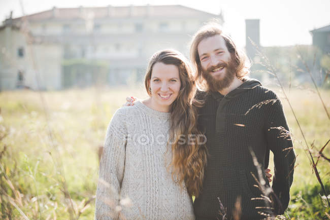 Молодая пара в поле улыбается, портрет — стоковое фото