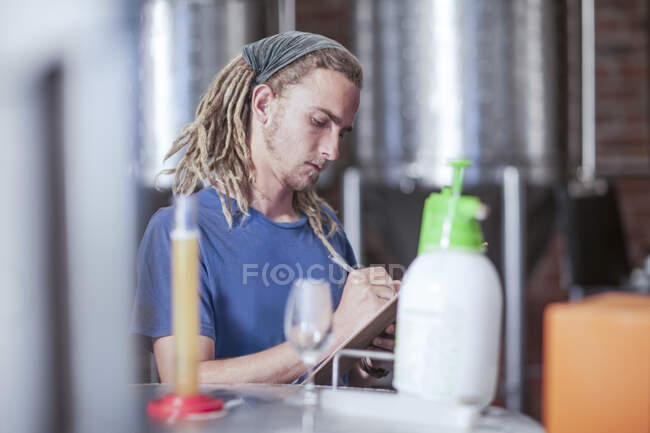 Cape Town, South Africa, young male writing down notes in brewry room — Stock Photo