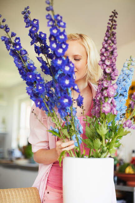 Frau arrangiert Blumen in Küche — Stockfoto
