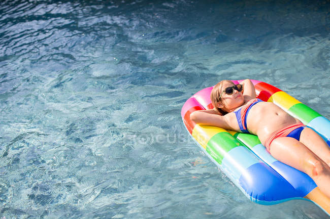 Девушка в бикини лежит на надувном в открытом бассейне — стоковое фото
