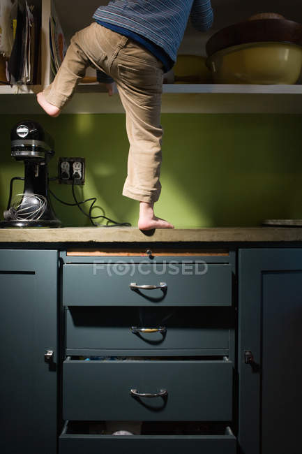 Boy climbing in kitchen — Stock Photo