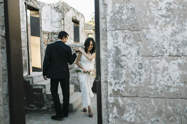 Noiva e noivo ao ar livre, de mãos dadas, sorrindo — Fotografia de Stock