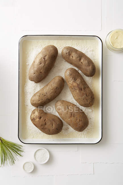 Top view of salt baked potatoes in roasting tin — Stock Photo