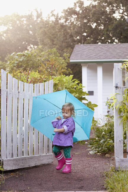 Female toddler walking in garden carrying umbrella — Stock Photo