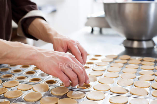 Imagen recortada de panadero moldeando pastelería en la cocina - foto de stock