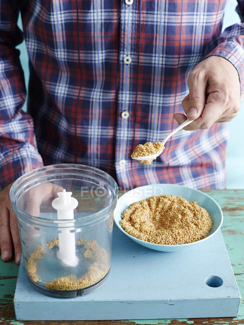 Mann bereitet frischen Senf Rezept Schritt 1, Senfkörner in der Küchenmaschine — Stockfoto