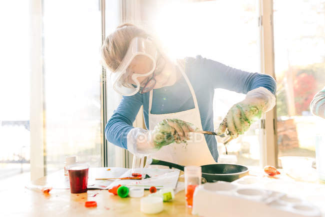 Дівчина робить науковий експеримент, поливаючи зелену рідину в сковороду — стокове фото
