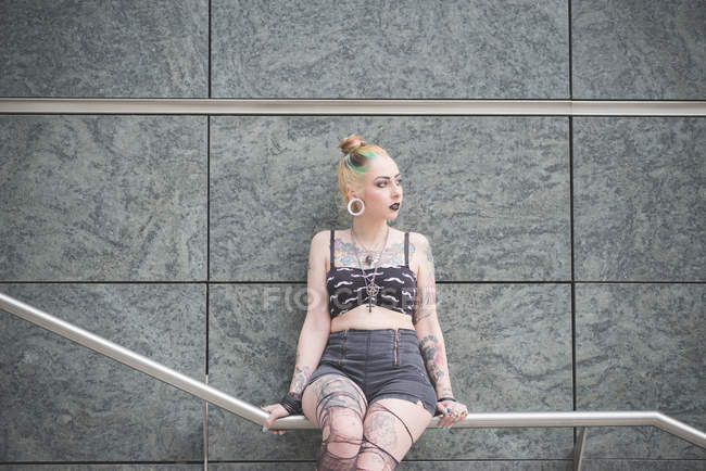 Portrait d'une jeune punk tatouée assise sur une rampe de métro — Photo de stock