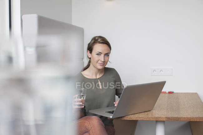 Portrait de jeune femme utilisant un ordinateur portable au bureau — Photo de stock