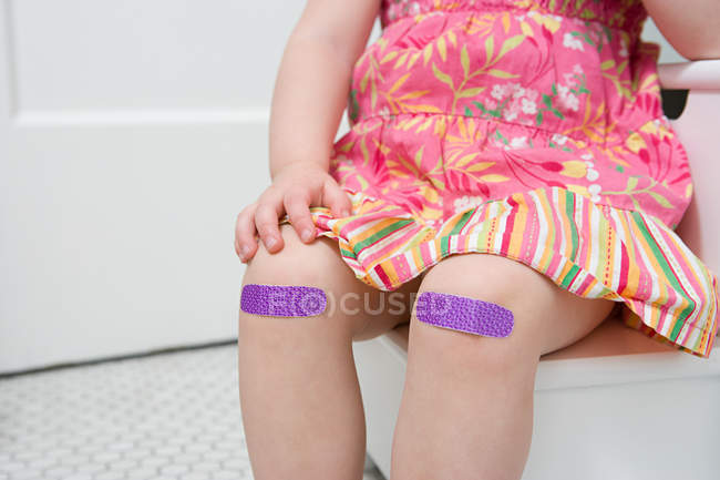Chica con yesos en sus rodillas - foto de stock