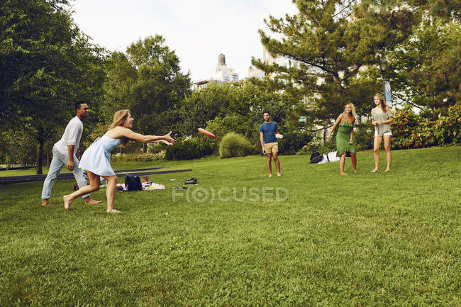 П'ять дорослих друзів грають з літаючим диском у парку — стокове фото